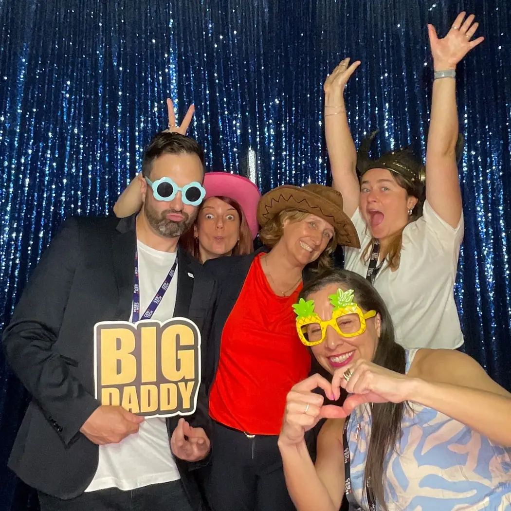 Un equipo con accesorios en el photobooth con fondo azul de lentejuelas en un evento corporativo en Miami