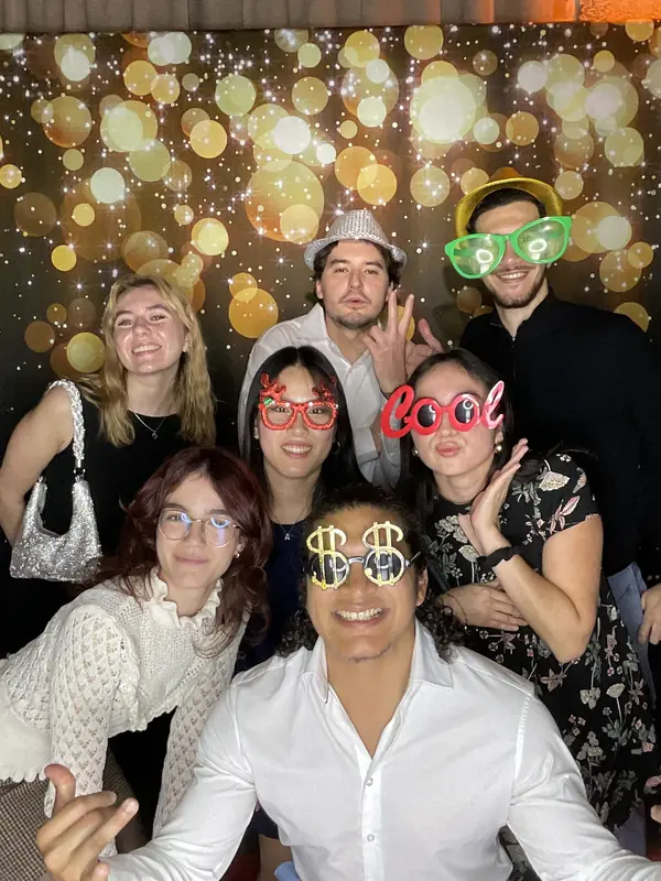 Coworkers in novelty glasses at a Miami holiday party photo booth