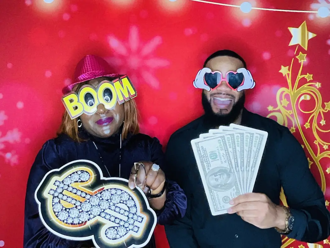 Invitados con accesorios en el photobooth con fondo rojo en una fiesta corporativa en Miami
