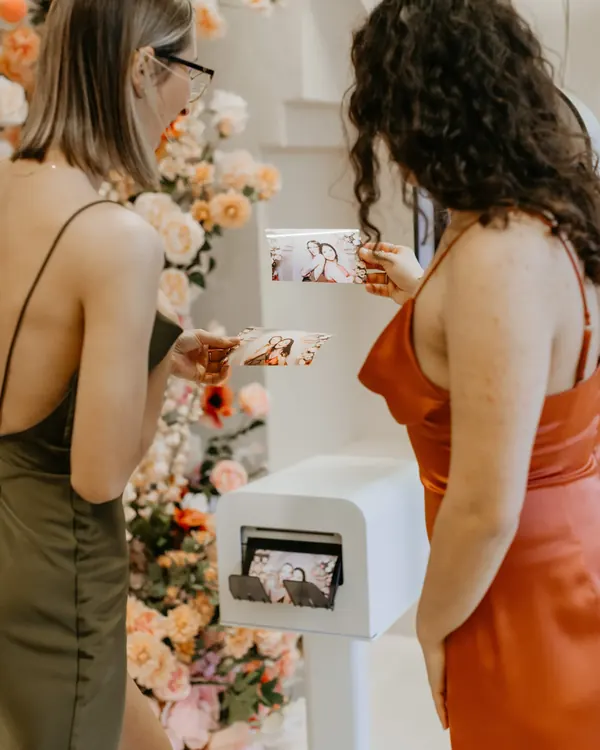 Guests holding fresh prints beside the DSLR photo booth