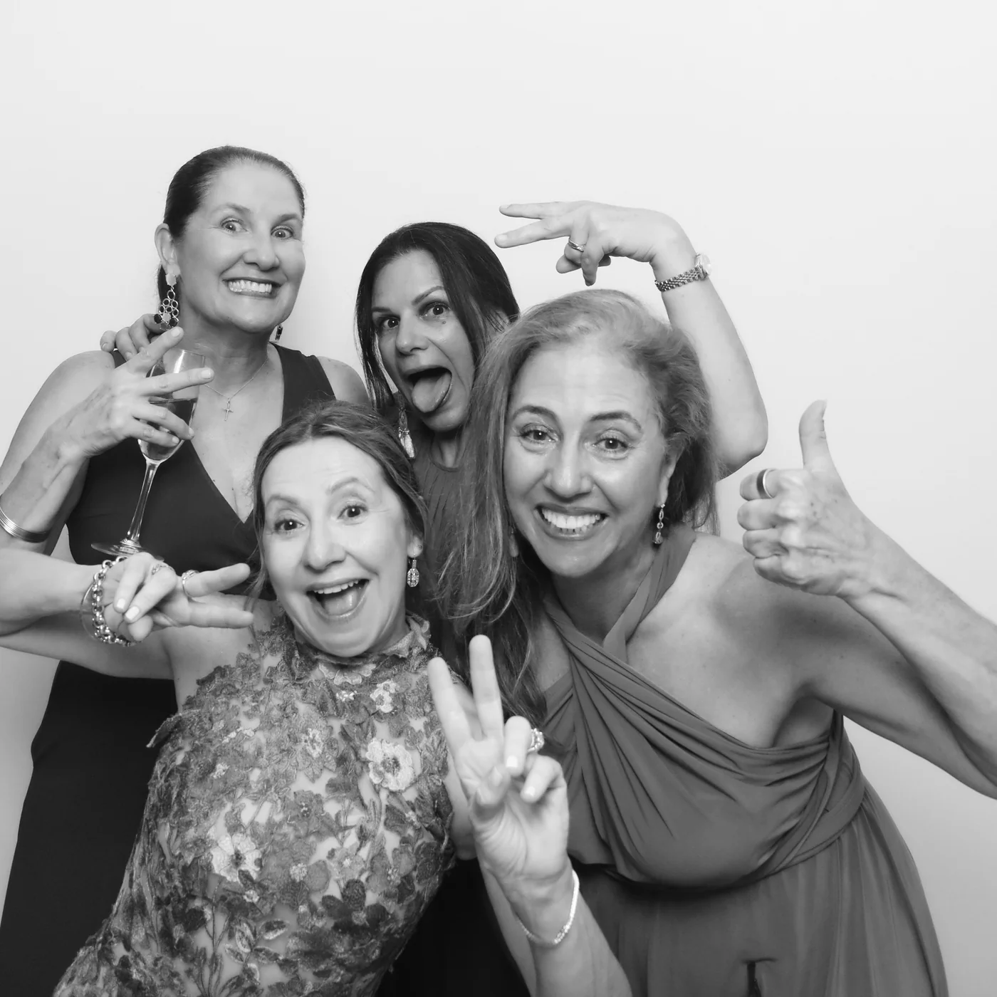 Four guests making playful poses in a black-and-white Glam photo booth portrait