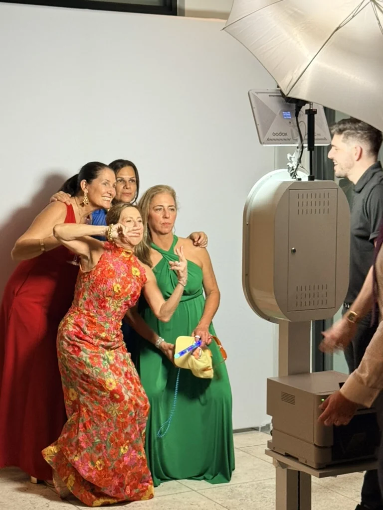 Guests posing while an Eleganza photo booth attendant operates the camera at an event