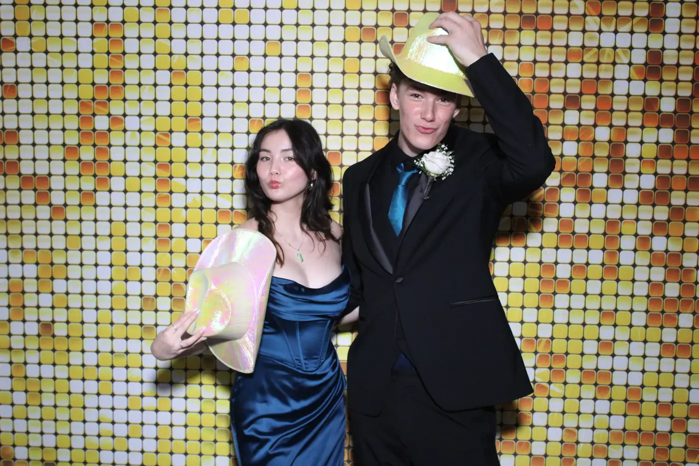 Una pareja de gala con sombreros divertidos en el photobooth del prom