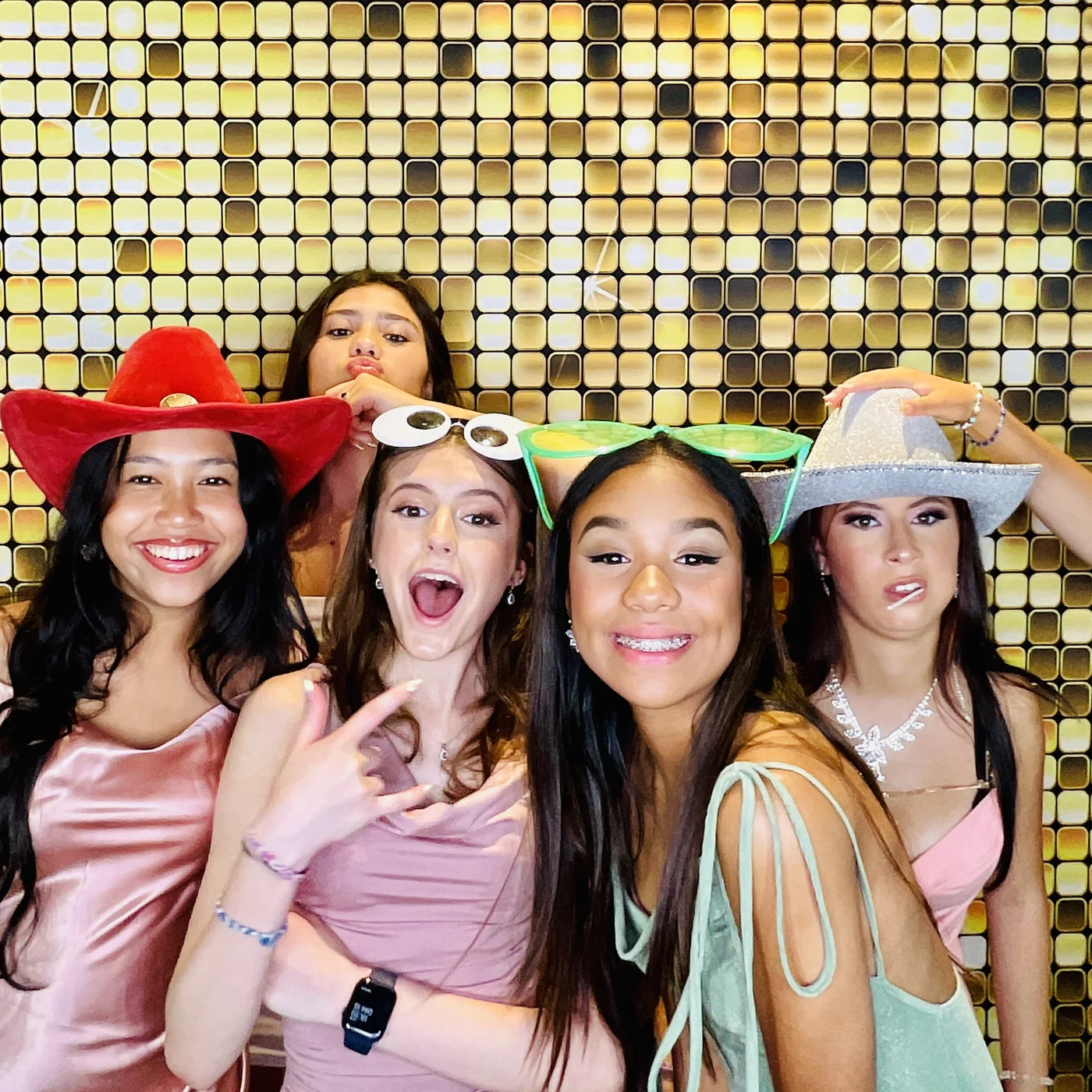 Amigas de la quinceañera con accesorios contra un fondo dorado en Miami