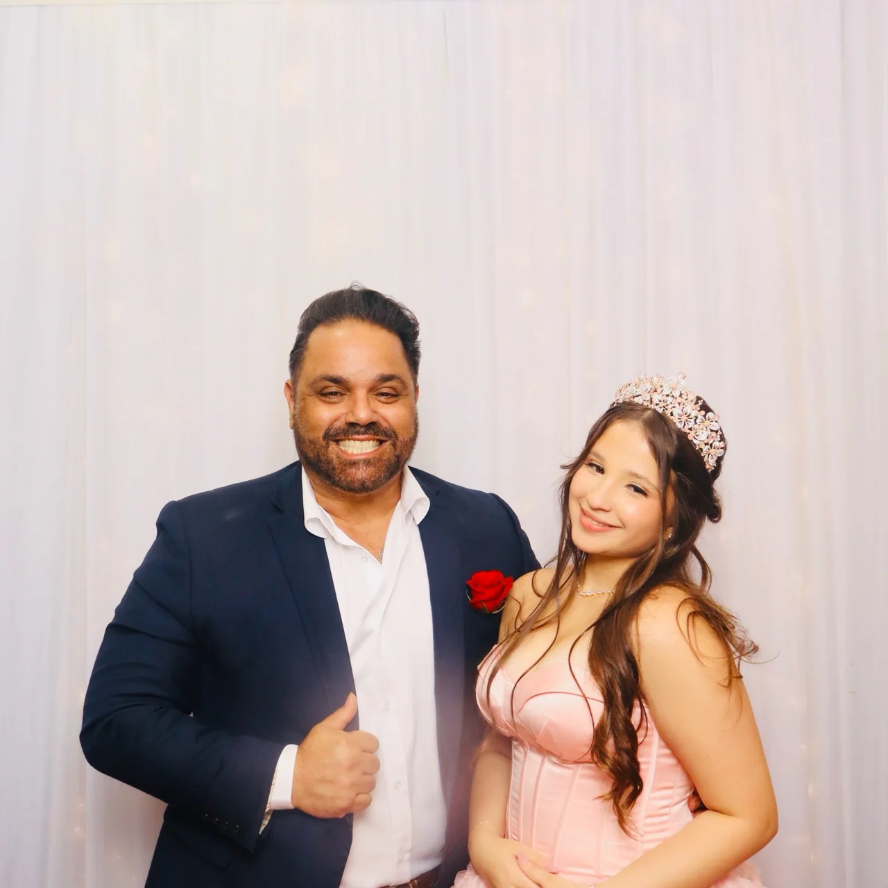 Quinceañera in a pink gown posing with a family member at the photo booth
