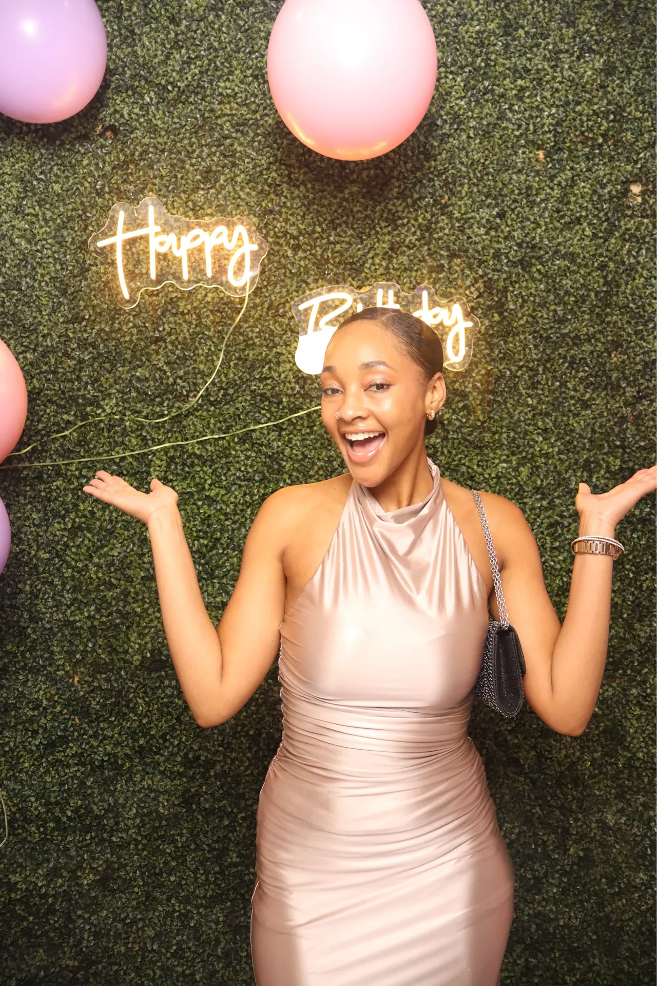 A guest poses under a glowing Happy Birthday sign at the DSLR photo booth