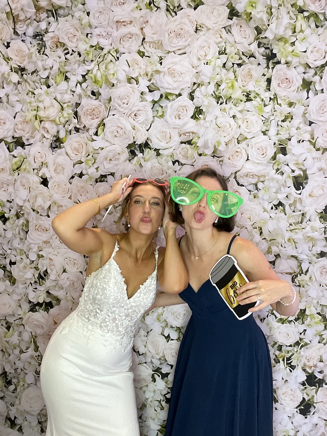 La novia y una amiga con lentes divertidos en el photobooth en una boda en Aventura