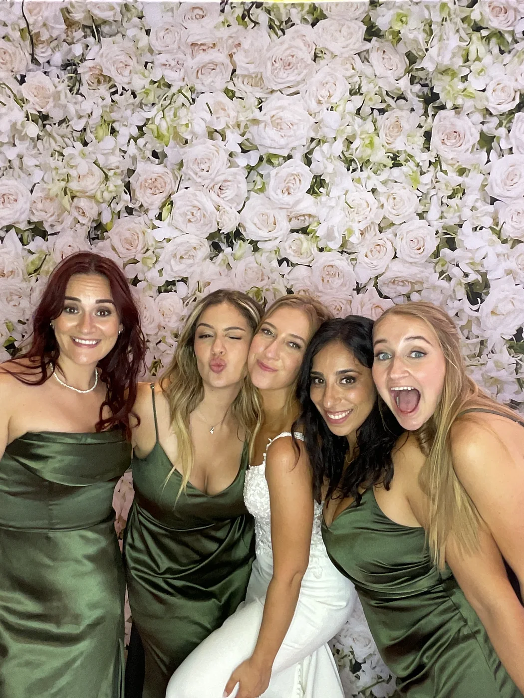 La novia y sus damas de honor en el photobooth con fondo floral en una boda en Aventura