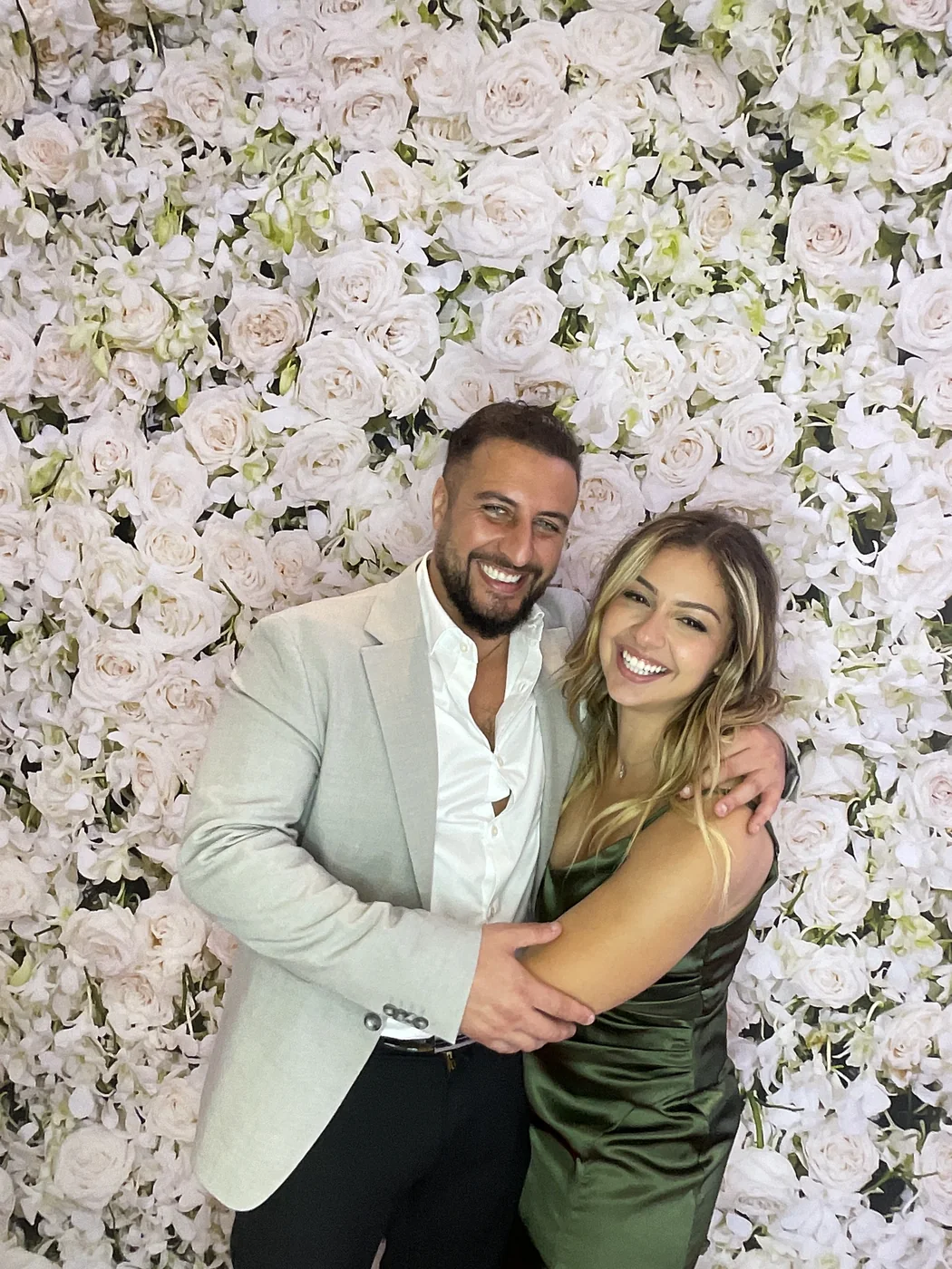 Una pareja abrazada en el photobooth con fondo floral en una boda en Aventura