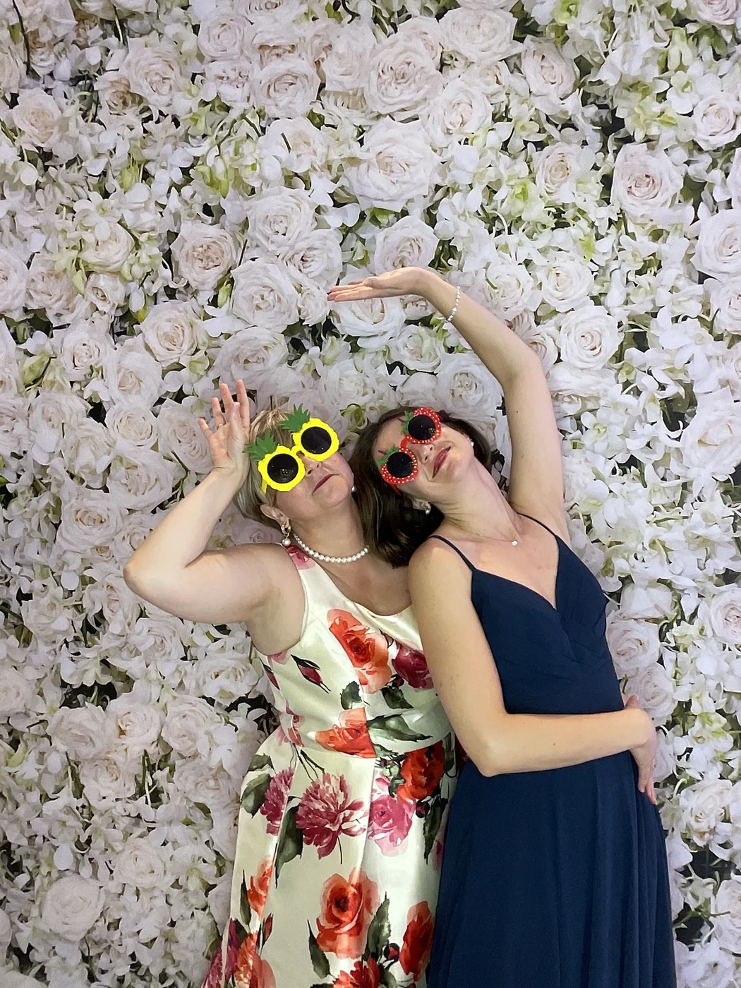 Dos invitados posando en el photobooth con fondo floral en una boda en Aventura
