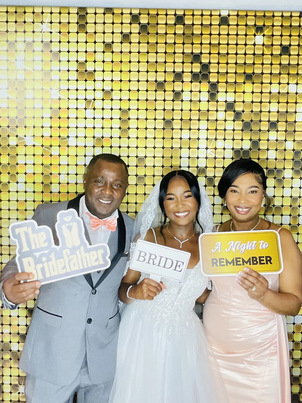 La novia con sus padres en el photobooth con fondo dorado en Miami