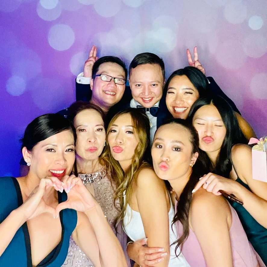 Wedding guests gathered at an Eleganza photo booth against a purple bokeh backdrop in Miami